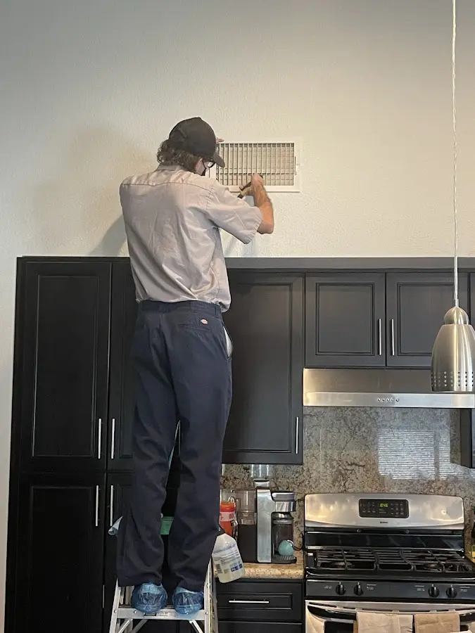 Technician inspecting an air vent during HVAC service in Aiea
